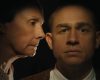 A cinematic image of an older woman on the verge of whispering something into a younger man's ear.