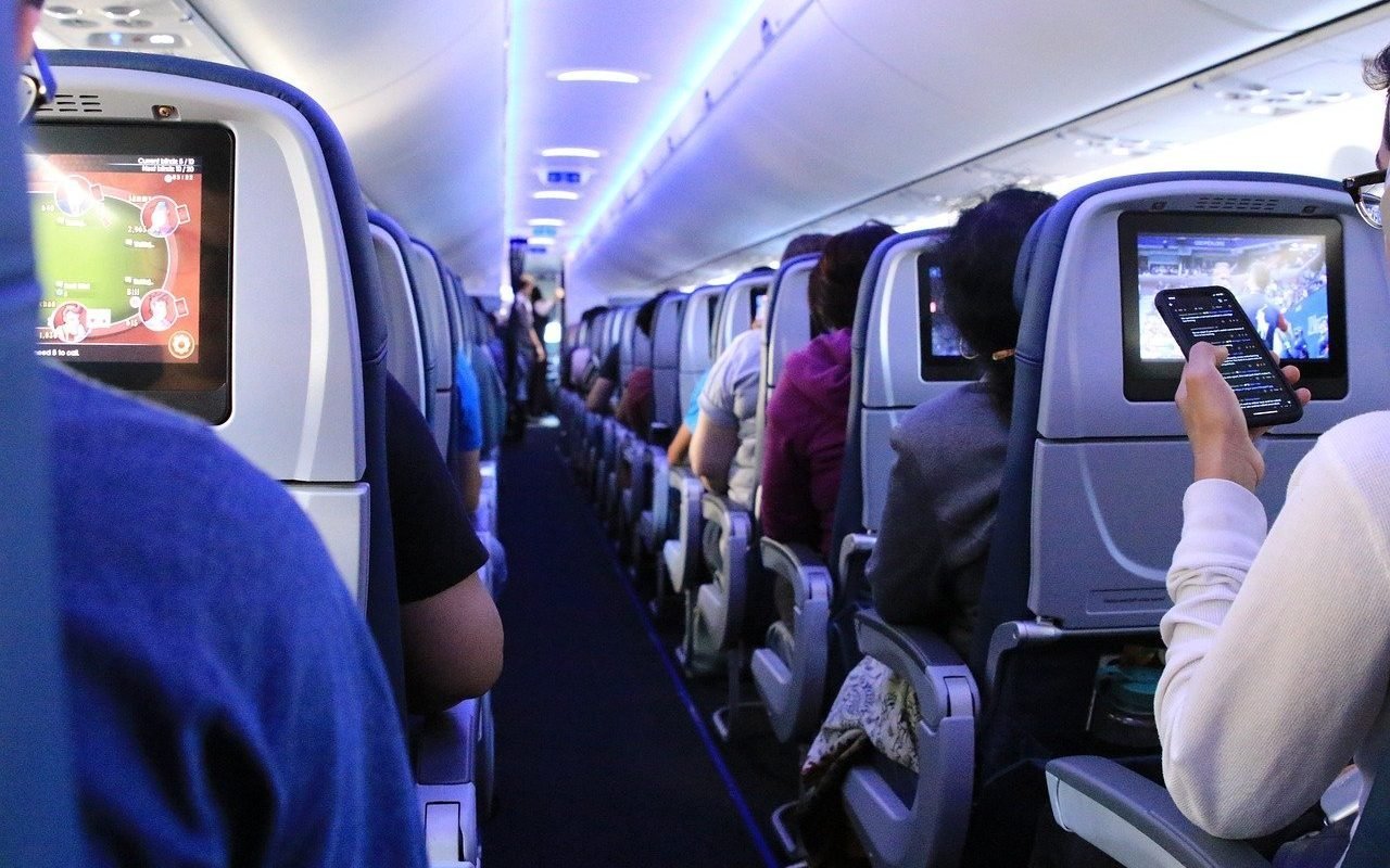 [ad_1] Oameni îmbrăcați în costume și cu pălării urcă respectuos în avion, fiecare având un mic bagaj de mână