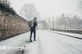Man walks along a snow covered street with a rucksack on his back