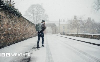 Man walks along a snow covered street with a rucksack on his back