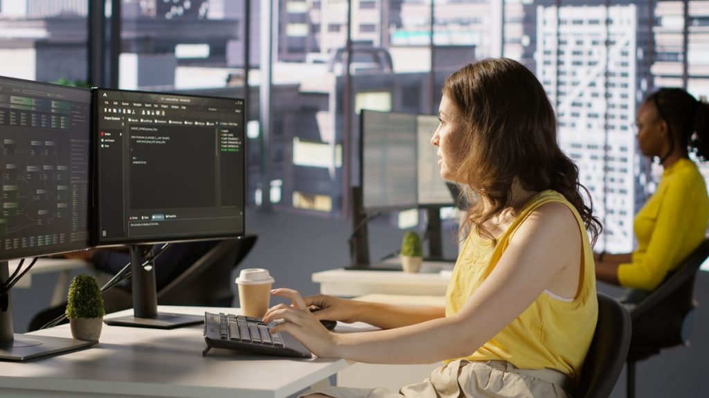 Woman at computer in a large office.