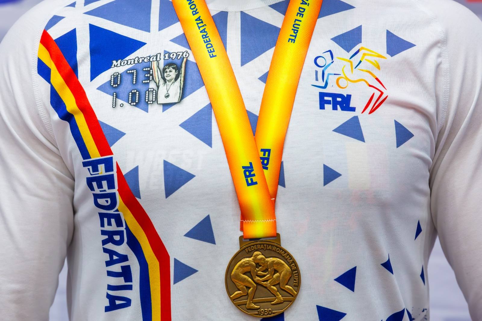 Nadia Comăneci, simbolul excelenței sportive, pe tricourile luptătorilor români La jumătate de secol de la momentul istoric când Nadia Comăneci obținea prima notă de zece din istoria gimnasticii, Federația Română de Lupte face un gest inedit